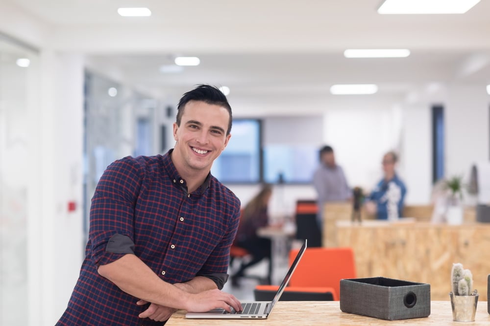 Portrait of a young businessman in leisure activities in a modern startup office, working on a laptop.